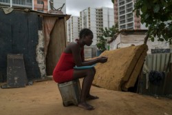 A woman outside her home in the shadow of a large gated housing project away from Luanda.jpg